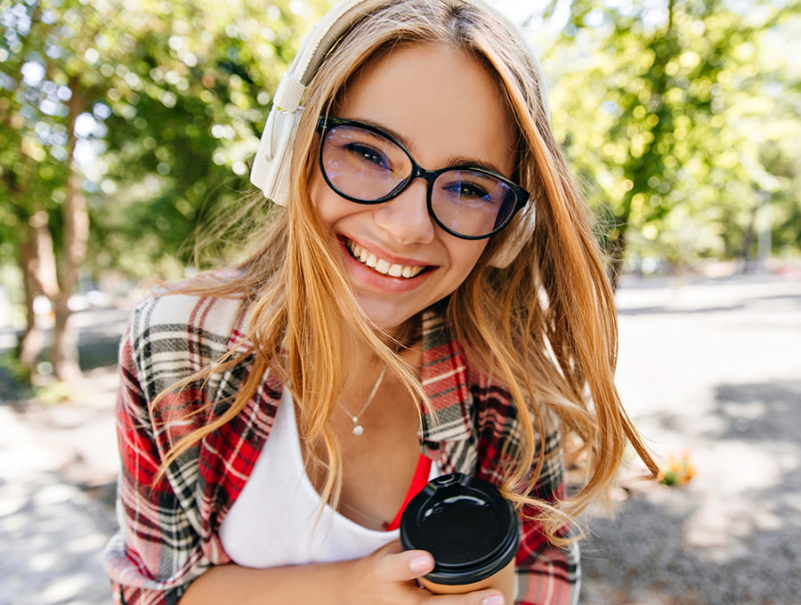 Chica con la piel muy bien cuidada se toma un café en el parque de su ciudad.