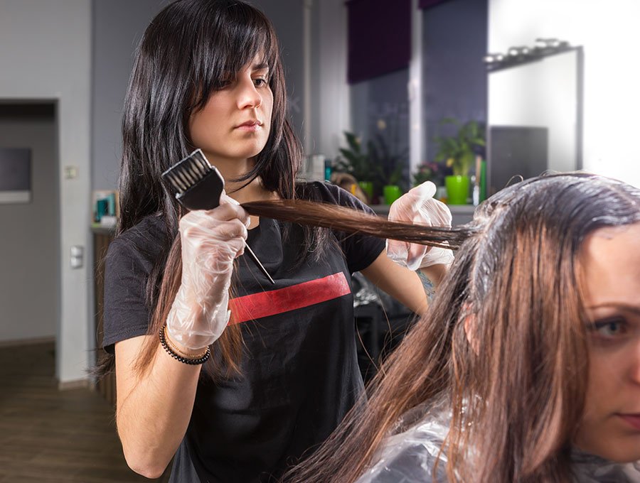 Estilista aplica tinte sobre el cabello de una clienta.