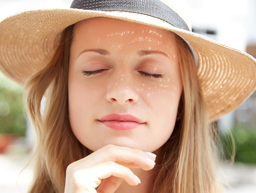 Mujer joven disfruta del día soleado tras ponerse protector facial de la roche con factor 50.